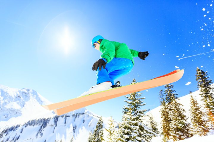 a man flying through the air while riding a snow board